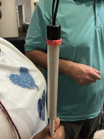 Student holding a tactile identifier attached to a white cane